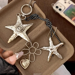 Detailed macro of vintage silver starfish pendants and gold heart on woven cord
