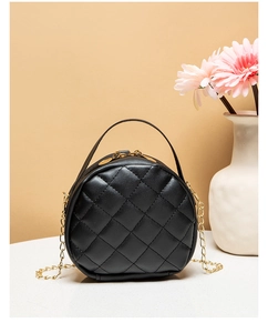 Detail of round black quilted handbag with gold zipper and stylish chain strap