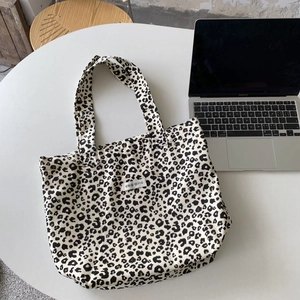 Macro shot of leopard print canvas tote bag next to laptop on desk
