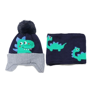 Detailed close-up of navy knit hat and scarf set featuring green dinosaur embroidery