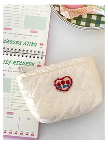Dettaglio della trapuntatura a cuore e del ricamo a tulipano sulla borsa color crema