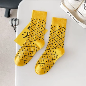 Yellow crew cotton socks with black pineapple pattern for men and women on white desk