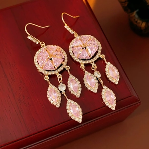 Macro detail of vintage gold earrings with pink gemstones on a luxury jewelry box