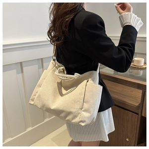 Detail view of beige corduroy tote bag with side pockets and adjustable strap