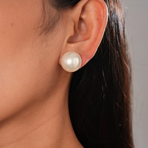 Close-up of a large 14mm round faux pearl stud earring worn elegantly by a female model
