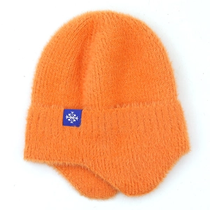 Close-up of bright orange fuzzy knit beanie with earflaps and blue snowflake patch