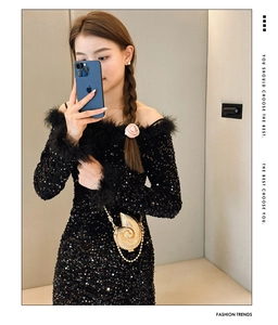 Close-up of shell-shaped metal handbag paired with a sequined black feather dress