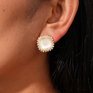 Close-up of gold cat-eye stone stud earring with halo crystal frame on model ear