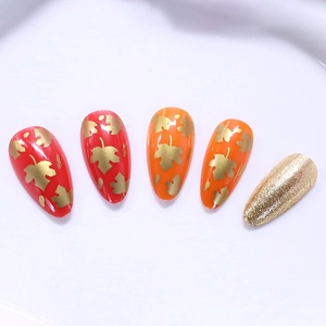 Elegant autumn almond press-on nails with maple leaf patterns and gold glitter finish
