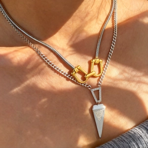 Layered gold stirrup buckle and silver triangle pendant necklace on female neck