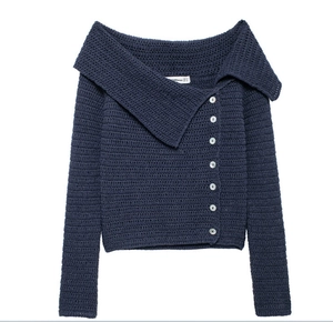 Dettaglio del cardigan in maglia blu scuro con bottoni diagonali e trama a uncinetto