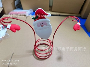 Detailed view of a metal Christmas wine bottle holder featuring Santa Claus and red glove motif