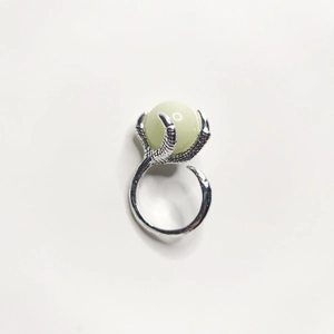 Detailed view of vintage silver dragon claw holding a luminous green crystal ball pendant