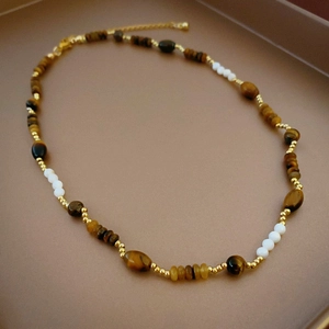 Detailed macro view of tiger eye beads with gold metallic spacers on a beaded necklace