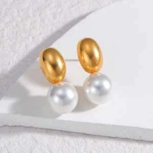 Detailed view of elegant gold oval studs with white pearls on a textured stone surface