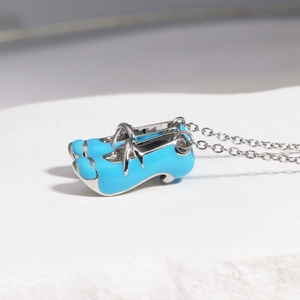 Detail shot of mini blue ballet shoe pendants with silver chain on textured background