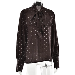 Détail du chemisier marron à pois avec un nœud décoratif au décolleté et aux poignets