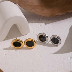Macro shot of minimalist gold and silver geometric earrings with black oval center inlay