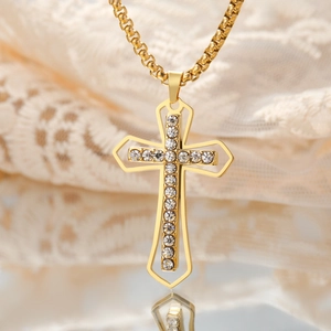 Macro shot of gold cross pendant with white zircon inlays and fine link chain on lace