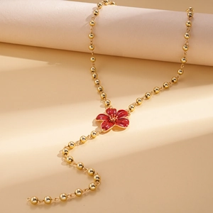 Detail of red enamel flower pendant on golden beaded chain with retro elegant styling