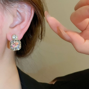 Close-up of vintage square geometric drop earrings with crystals on a model ear