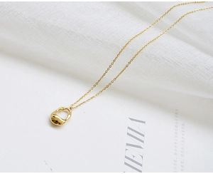 Close-up of a gold teardrop pendant with a mirror-polished finish on a fine chain