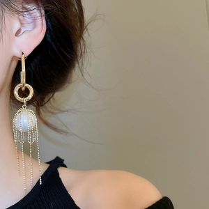 Detail of elegant gold long tassel earrings featuring pearls on a model's side profile