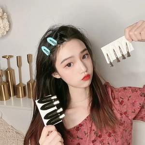 Detail of metal leaf-shaped hair clips for styling, showing black and silver variants