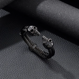 Macro shot of punk style black braided wire steel bracelet featuring twin skull heads
