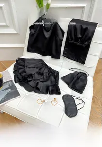 Detailed flat lay of black silk pajamas set including camisole, trousers and eye mask