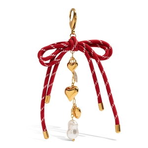 Red bow bag charm with baroque pearl and golden heart pendants on white background