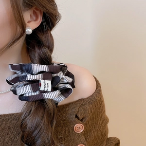 Detail of striped brown scrunchie on low ponytail with a custom brand fabric label