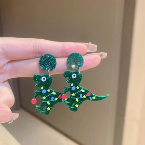 Detailed close-up of green acrylic dinosaur earrings with festive Christmas light patterns