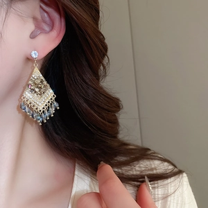 Close-up of diamond rhombus earrings with blue and grey teardrop bead tassels