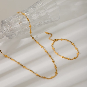 Detailansicht von Gold-Edelstahl-Set aus Kreuzkette und Armband auf strukturiertem Hintergrund