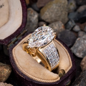 Macro shot of a pear-shaped diamond ring with pavé diamonds in a vintage velvet box