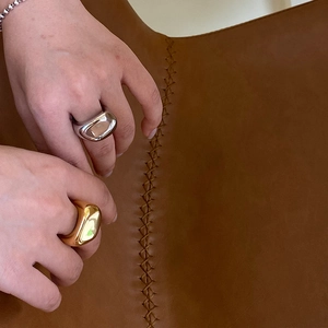 Anillos minimalistas gruesos e irregulares en oro y plata sobre fondo de cuero