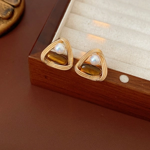 Detail of vintage triangular earrings with tiger eye stone and pearl on a jewelry box