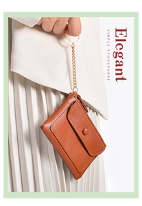 Brown leather mini coin purse with gold keychain chain held by a model in elegant style