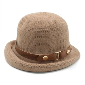 Détail du chapeau tricoté camel avec lanière en cuir marron et rivets en métal doré