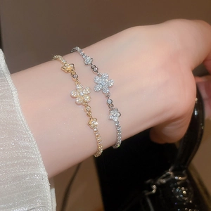 Close-up of sparkling zircon flower bracelets in gold and silver finishes on a wrist
