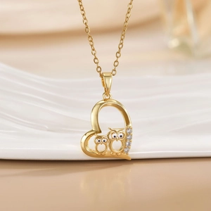 Golden heart owl necklace with sparkling crystals on a minimalist white background