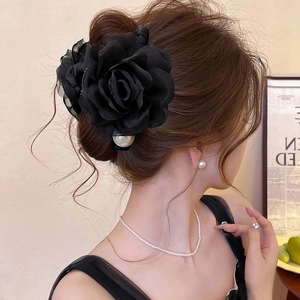 Detail of elegant black fabric rose hair claw with white pearls on model's hair