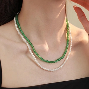 Detail of layered necklace featuring white pearls and green agate beads worn on neck