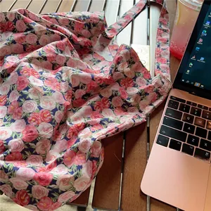 Detail of vintage rose pattern cotton tote bag on a wooden desk with a laptop