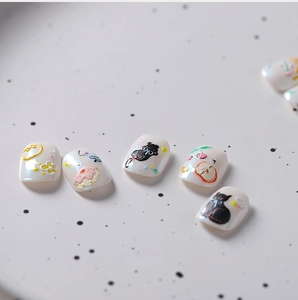 Macro shot of cartoon 3D nail stickers featuring black cats and floral patterns