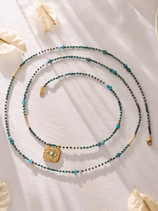 Detail of turquoise beaded necklace with golden Evil Eye pendant and zircon stones
