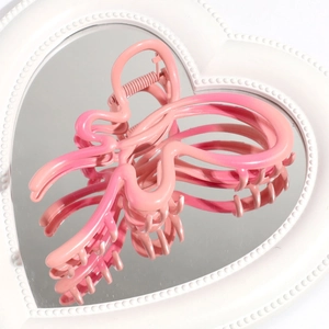 Detailed view of a pink gradient butterfly hair claw on a decorative heart-shaped mirror tray