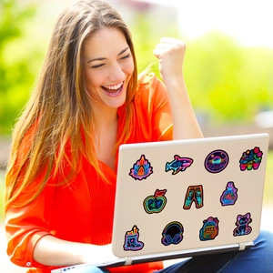 Neon style decorative stickers on a white laptop used outdoors with natural elements