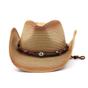 Detail of woven straw cowboy hat with evil eye ornament and brown gradient texture